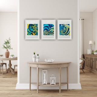 Three framed abstract artworks on a wall above a wooden table in a room.
