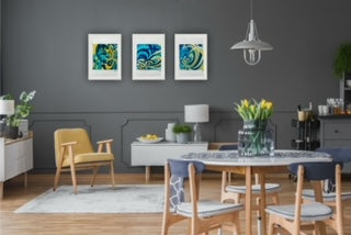 Dining room with grey walls, wooden furniture, and a three colourful modern prints framed on the wall.