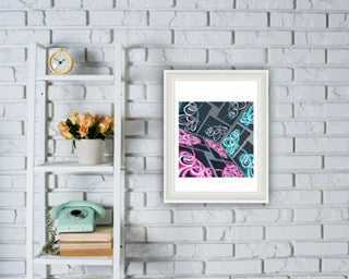 Framed modern paper artwork, framed on a white brick wall with a shelf containing books and a clock.
