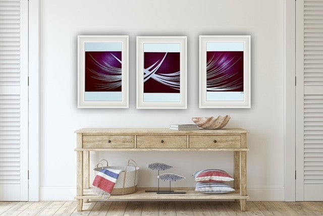 Three framed red abstract artworks on a wall above a wooden console table.
