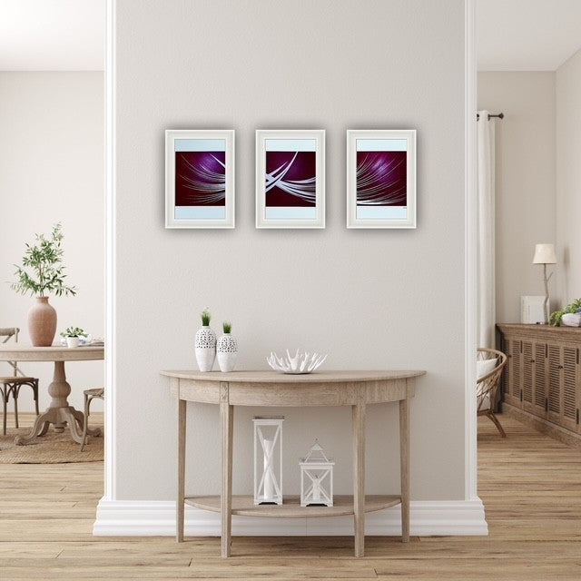 Three red abstract art pieces on a wall above a wooden console table.